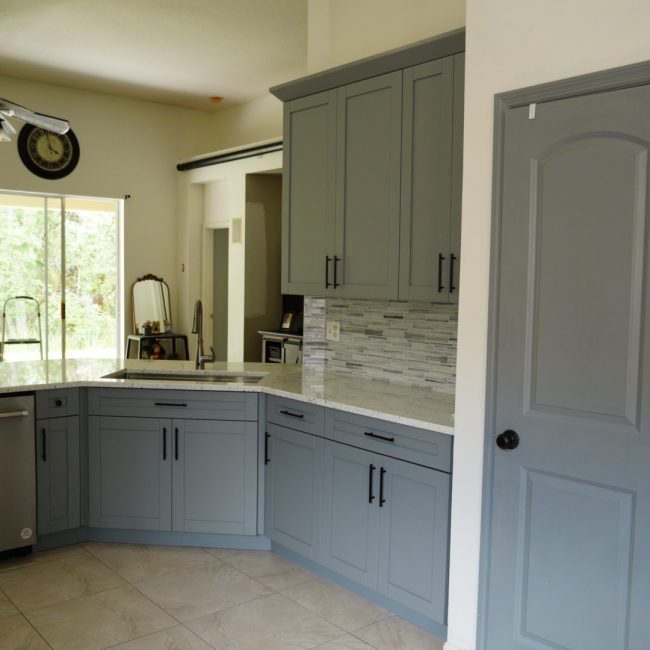 Modern kitchen remodel with slate gray shaker cabinets and white granite countertops.