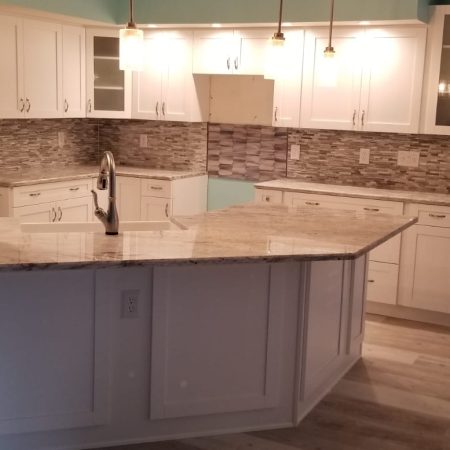 Modern kitchen with white cabinetry and marble countertops.