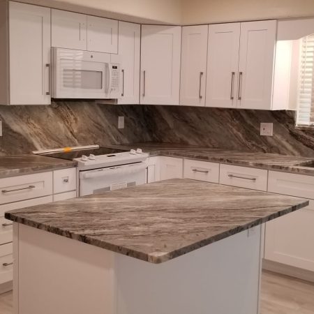 Modern kitchen with marble countertops and white cabinetry.