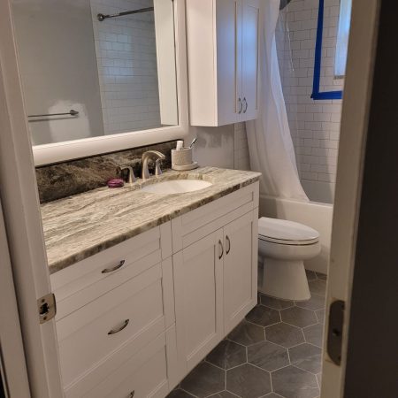 Modern bathroom with white cabinetry and marble countertop.